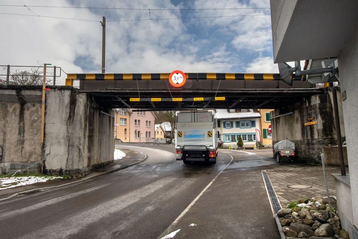 Ein Lastwagen fährt unter einer Brücke durch.